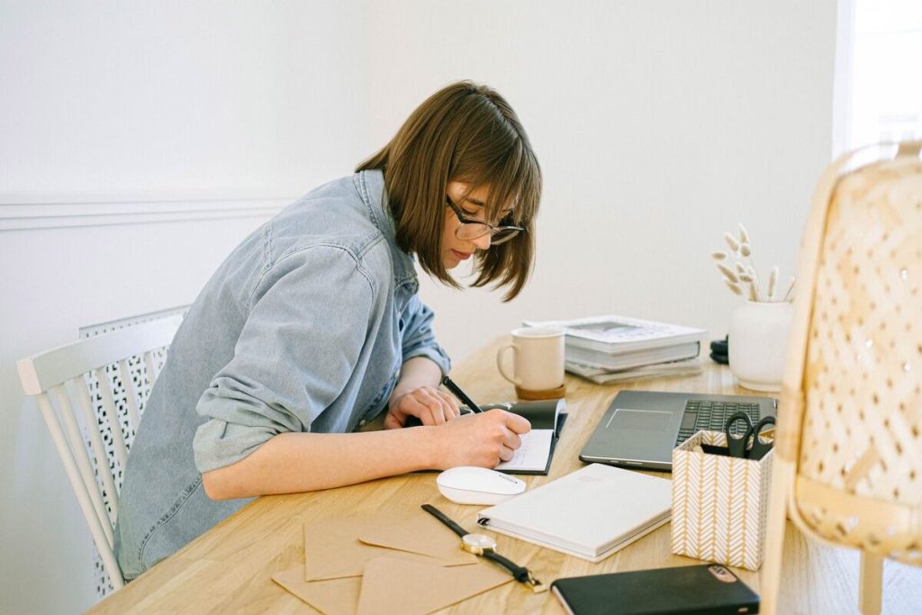 Woman sitting on a desk writing