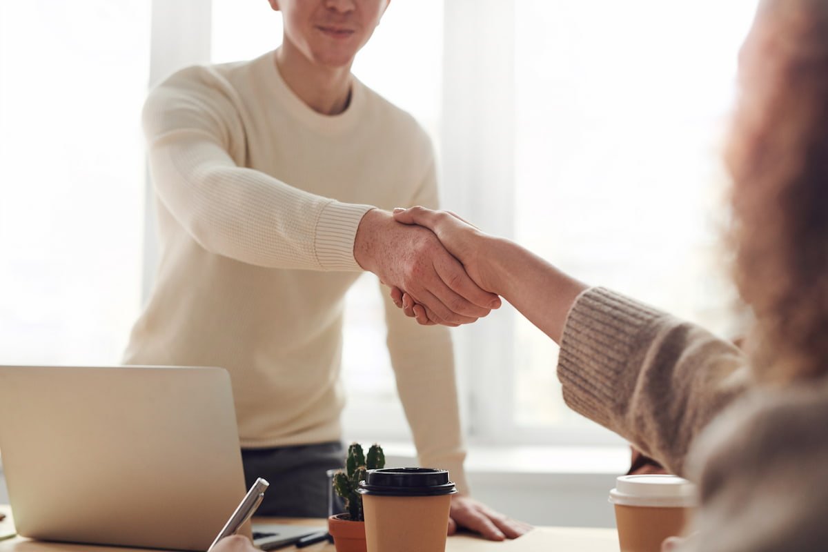 man and woman shaking hands over a desk