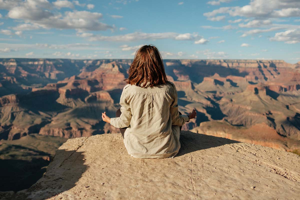 Woman meditating above canyon