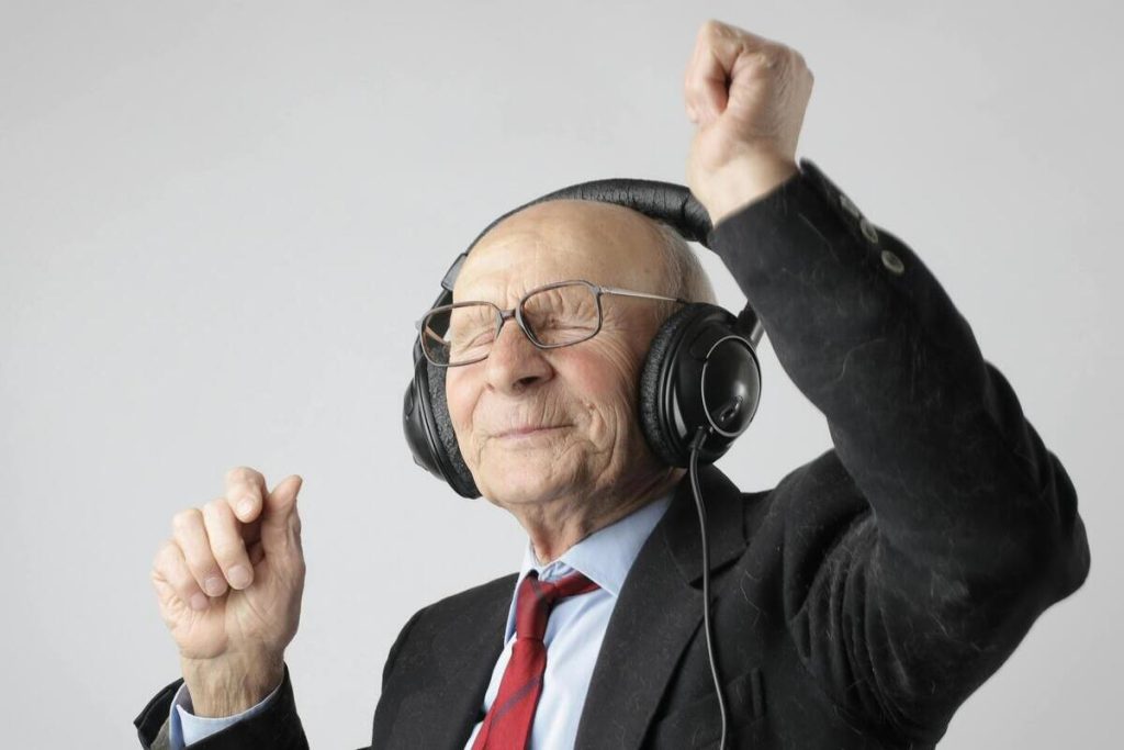 Old man wearing headphones and dancing