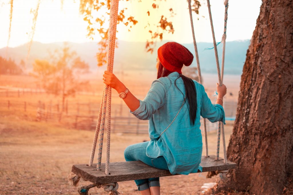 optimistic woman on swing at sunset